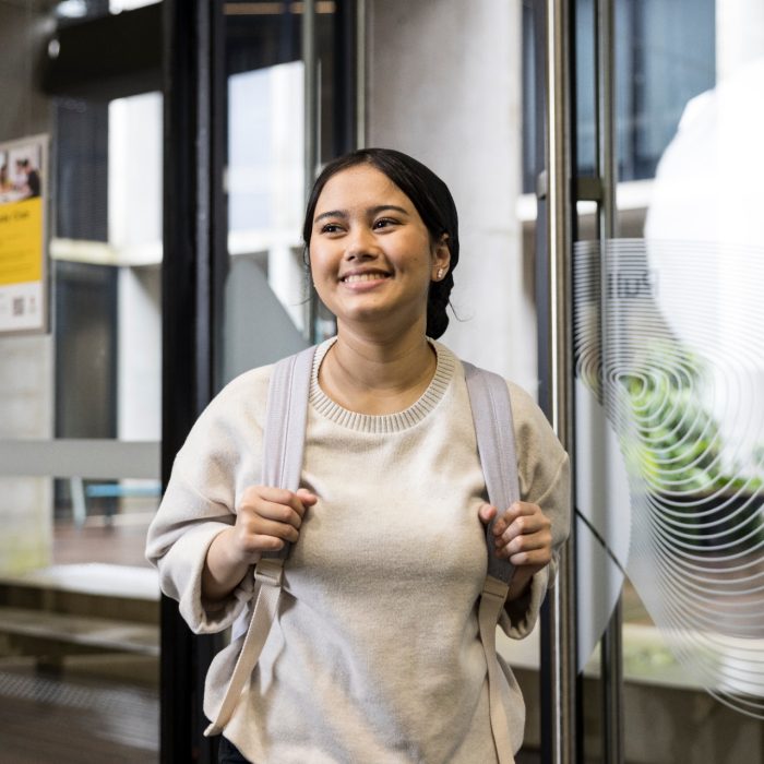 Student walking through door smiling at Student Services