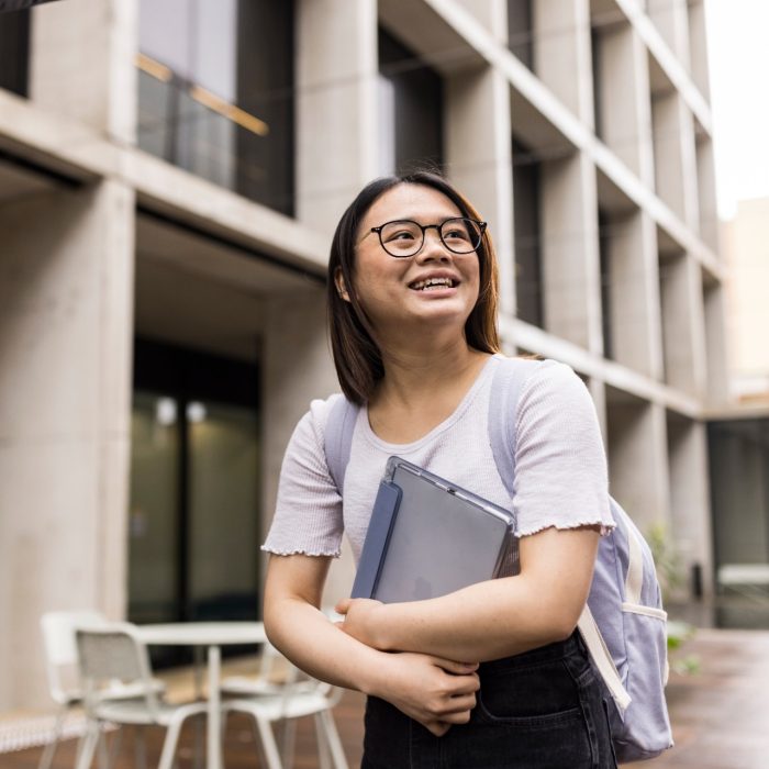 Student (Natalie) walking through the L5 courtyard with backpack and tablet