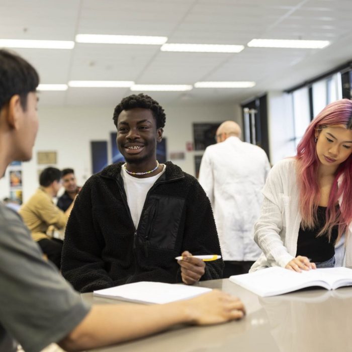 3 young students in class with open books