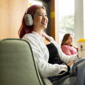 Student with headphones and coffee smiling