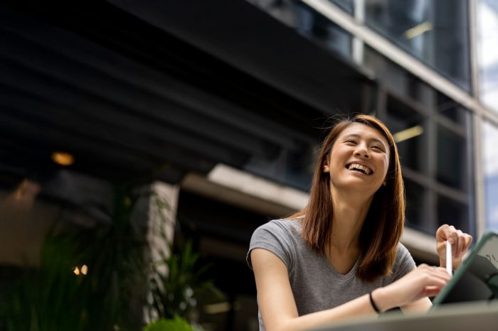 Student with iPad in courtyard, smiling