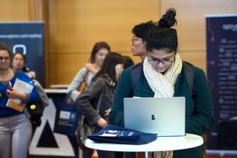 Young women using laptop at round table in crowded area