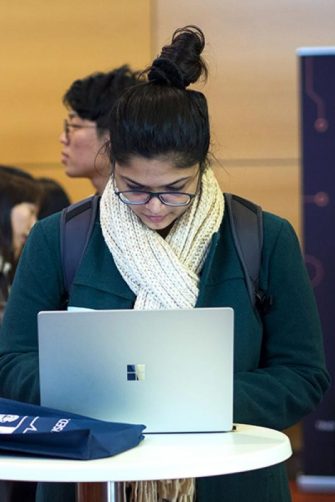 Young women using laptop at round table in crowded area