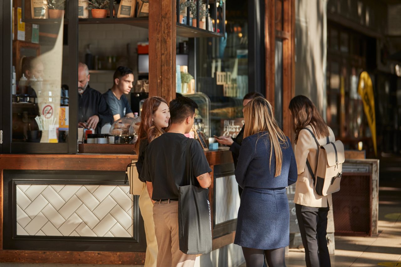 Students at standing with takeaway coffees at a coffee shop outdoors